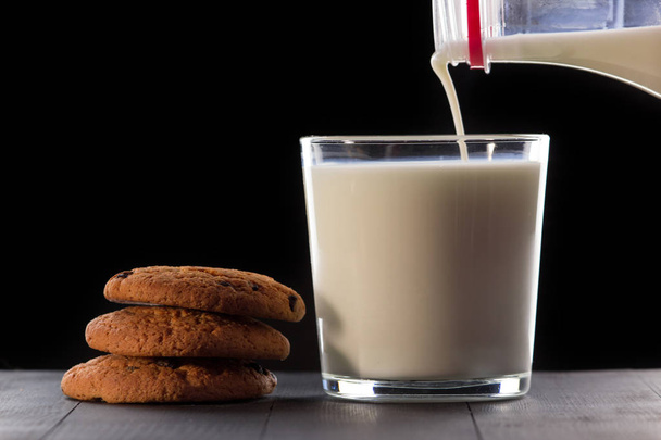 Milk with cookies on a black background - 写真・画像