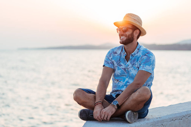 Молодий чоловік насолоджується заходом сонця біля моря
 - Фото, зображення