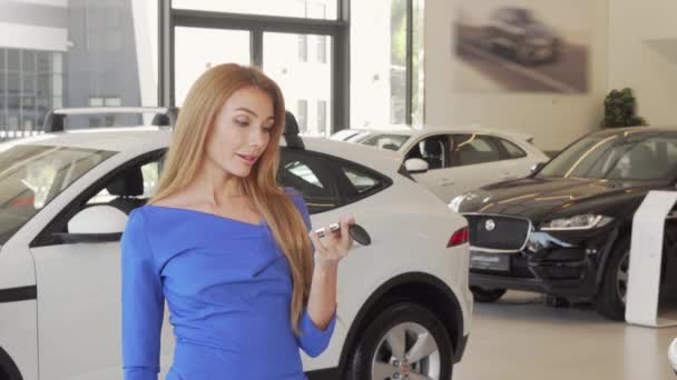Hermosa mujer feliz sosteniendo la llave de su coche nuevo en el concesionario
 - Imágenes, Vídeo