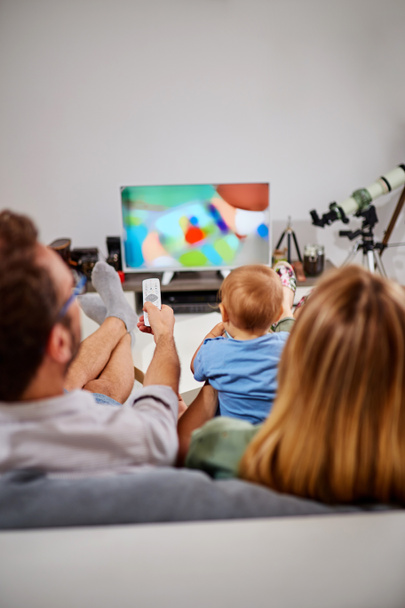 Fiatal szülők tévénézés a Baby Boy. - Fotó, kép