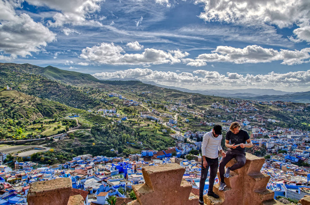 Turista observando una vista panorámica de la ciudad azul de Chefchaouen desde la puerta fortificada, Marruecos
 - Foto, imagen