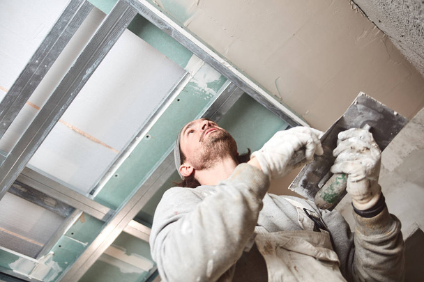 Trabalhador da construção civil reboco paredes de gesso dentro da casa
. - Foto, Imagem