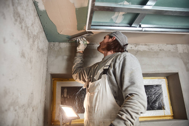 Trabalhador da construção civil reboco paredes de gesso dentro da casa
. - Foto, Imagem