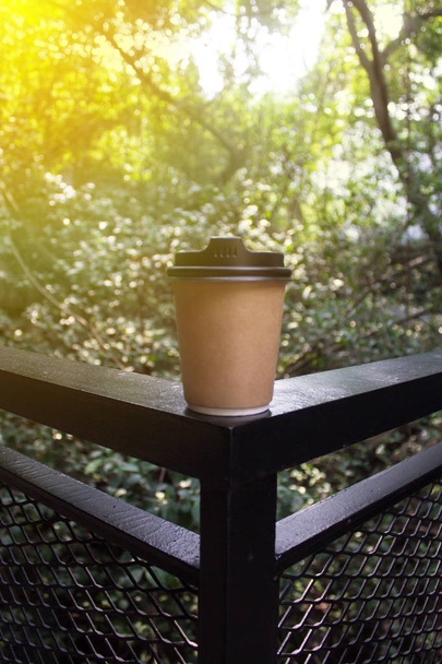 茶色のコーヒーリサイクルペーパーカップでショッピングモール内の手すりパネルから背景自然風景パノラマビューをぼかします。太陽光によるレイ - 写真・画像
