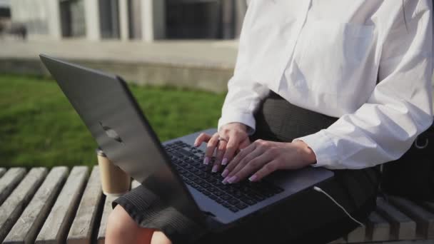 Jeune femme d'affaires assise à l'extérieur sur un banc avec ordinateur portable et de travail. - Séquence, vidéo