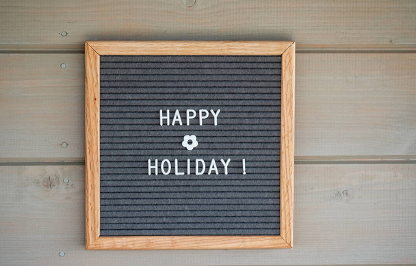 feltro Tabuleiro com texto em inglês feliz feriado em uma parede de madeira cinza
 - Foto, Imagem