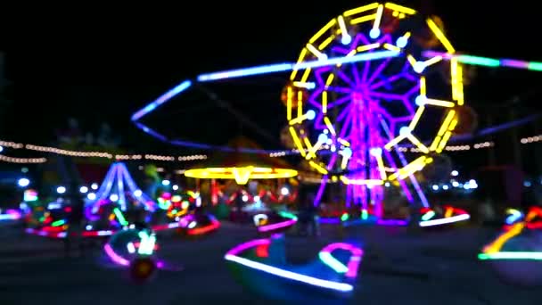 Mehrfarbiges Riesenrad und rollendes Neonlicht auf dem Nachtmarkt verschwimmen - Filmmaterial, Video