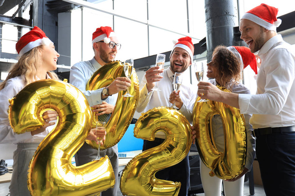 Business people are celebrating holiday in modern office drinking champagne and having fun in coworking. Merry Christmas and Happy New Year 2020. - Foto, Imagem