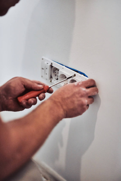 Villanyszerelő a fali drótok javítása/rögzítése. - Fotó, kép