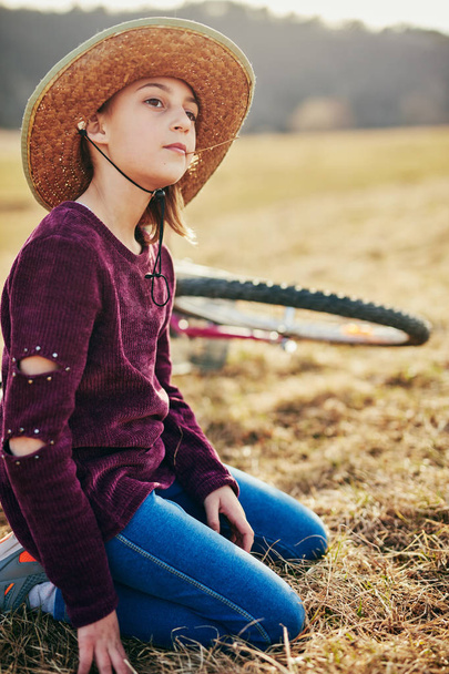 Cute little ten year old girl with bicycle on countryside meadow - Foto, Bild