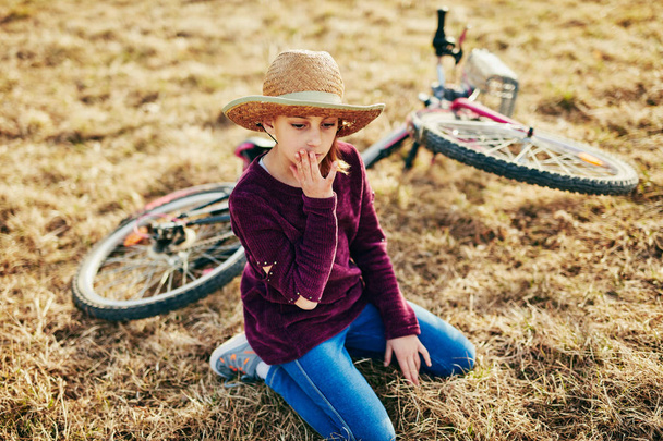 Χαριτωμένο μικρό δέκα χρονών κορίτσι με ποδήλατο στο λιβάδι ύπαιθρο - Φωτογραφία, εικόνα