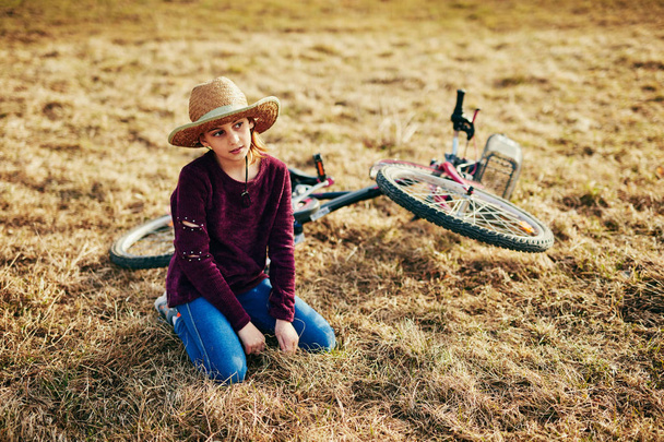 Χαριτωμένο μικρό δέκα χρονών κορίτσι με ποδήλατο στο λιβάδι ύπαιθρο - Φωτογραφία, εικόνα