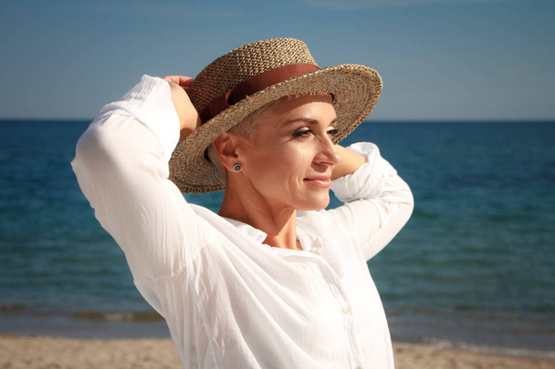 Прекрасна молода жінка з короткою стрижкою на пляжному капелюсі на пляжі
 - Фото, зображення