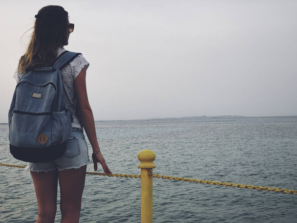 Samotna kobieta w pobliżu oceanu/morza na drewnianym molo. - Zdjęcie, obraz
