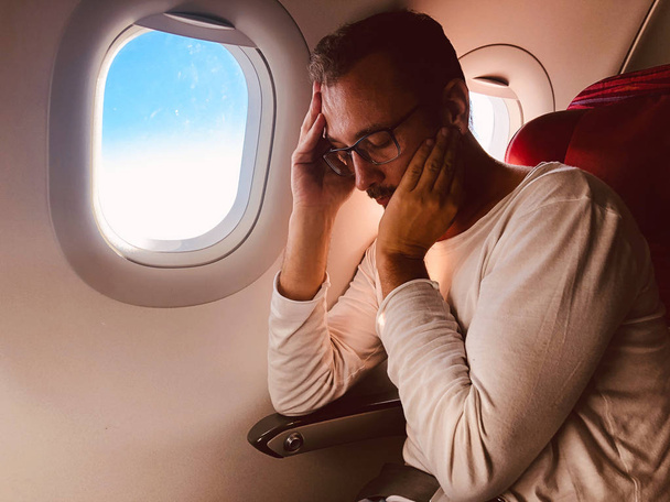 Уставший / больной пассажир на современном сиденье самолета рядом с победой
 - Фото, изображение