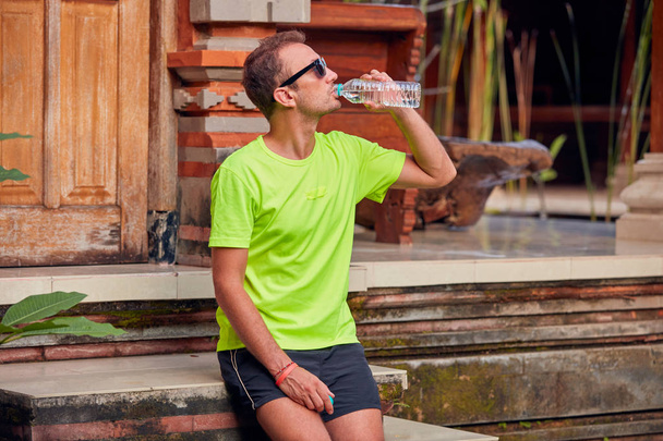 Sportler macht Pause mit einer Flasche Wasser. - Foto, Bild