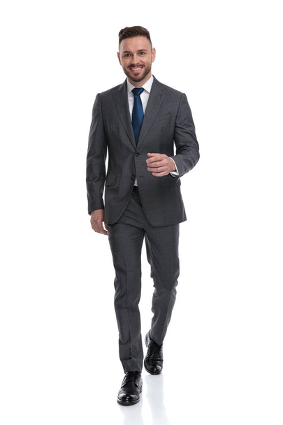 confident young businessman wearing suit and tie is walking forw - Photo, image