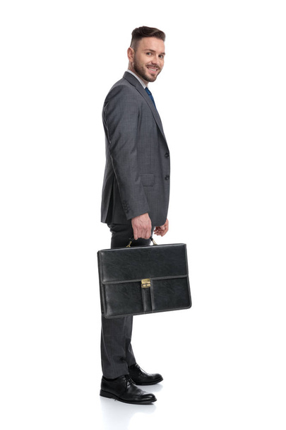 χαμογελαστός νεαρός επιχειρηματίας κρατώντας βαλίτσα περιμένει στην ουρά - Φωτογραφία, εικόνα