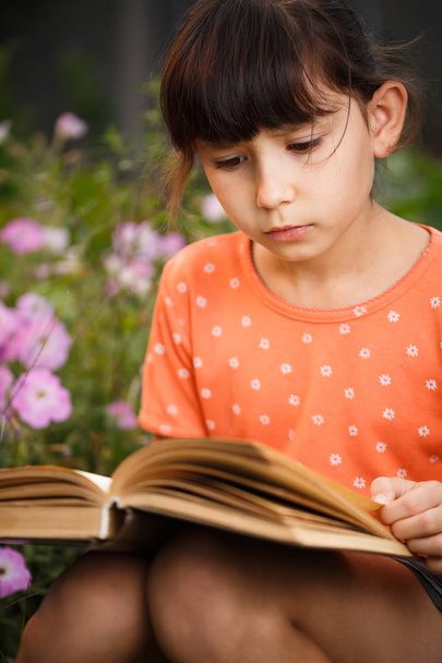 Cute girl is reading outdoors on an sunny day, international literacy day. - Photo, Image