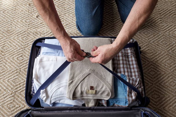 Мужчины старшего возраста упаковывают одежду в чемодан
. - Фото, изображение