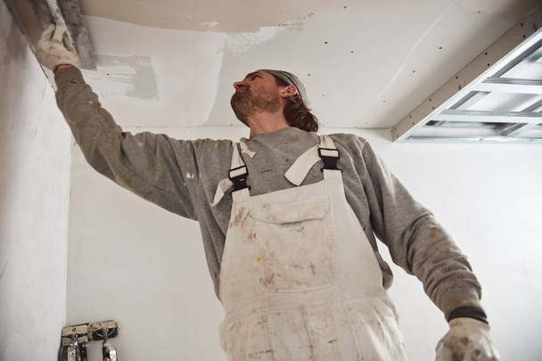 Workman plastering gypsum walls inside the house. - Фото, зображення