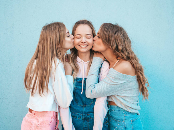 Portrait of three young beautiful smiling hipster girls in trendy summer clothes. Sexy carefree women posing in the street.Positive models kissing their friend in cheek - Fotoğraf, Görsel