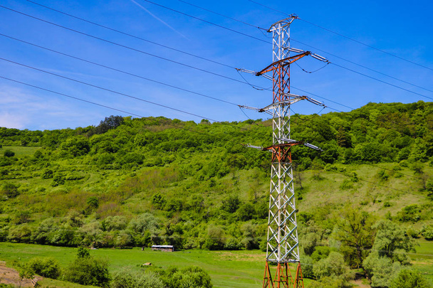 Reliance of high voltage power lines and blue sky on a background of green mountains. - Photo, Image