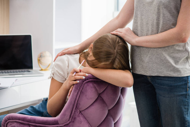 Sad school girl put head on chair with mother hand - Foto, immagini
