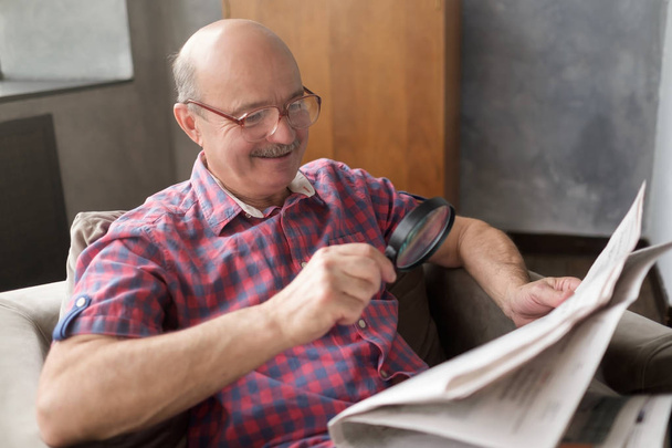 Старший іспаномовний чоловік читає газету зі збільшувальним склом
 - Фото, зображення