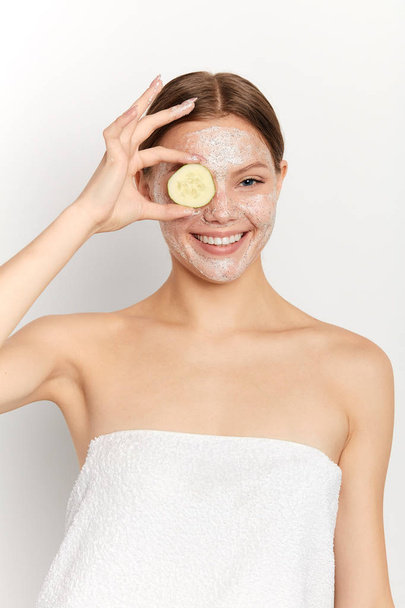 cheerful attractive girl having fun with a cucumber at spa salon - Photo, Image