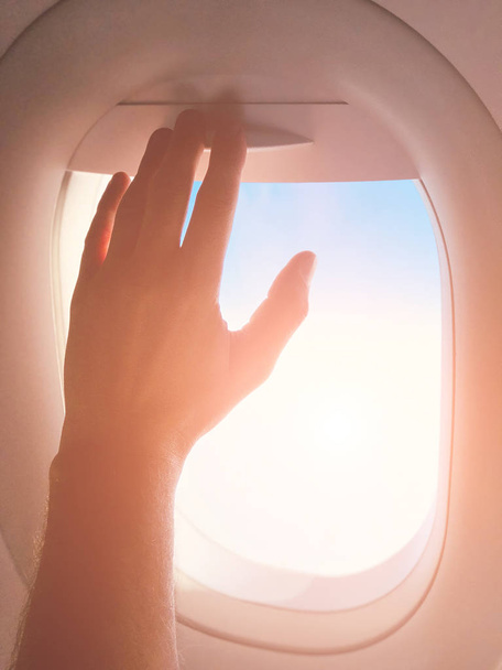 Passenger's hand closing the window shade on a modern airplane. - Φωτογραφία, εικόνα