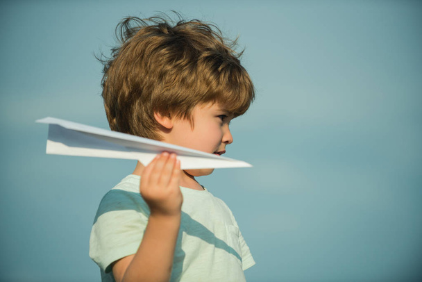 Happy child. Cute child on meadow with a toy paper airplane in the summer on the sky background. Family travel and vacation concept. - 写真・画像