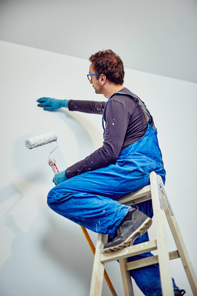 Worker painting walls inside the house - renovation fixes. - Photo, Image