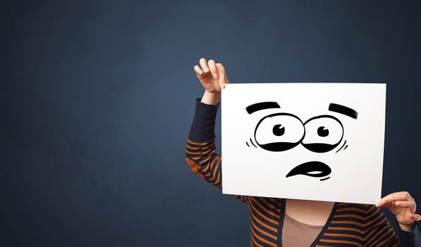 Osoba, která drží papír s funny emotikonu před její obličej - Fotografie, Obrázek