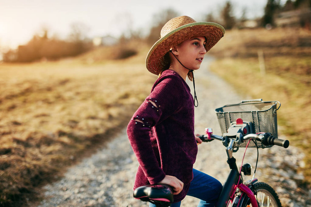 Χαριτωμένο μικρό δέκα χρονών κορίτσι ιππασία ποδήλατο στην ύπαιθρο. - Φωτογραφία, εικόνα
