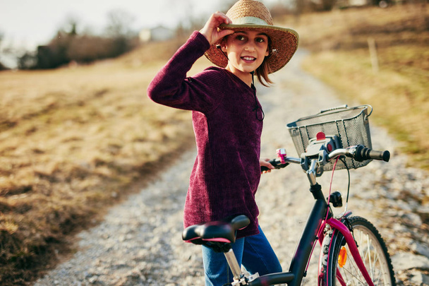 Cute little ten year old girl riding bicycle on countryside. - Photo, Image
