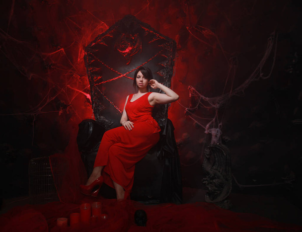 hermosa chica solitaria en vestido largo rojo en el trono de Halloween listo para la fiesta de miedo
 - Foto, Imagen