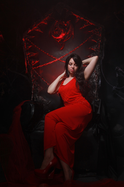 怖いパーティーの準備ができてハロウィーンの玉座に長い赤いドレスで美しい孤独な女の子 - 写真・画像