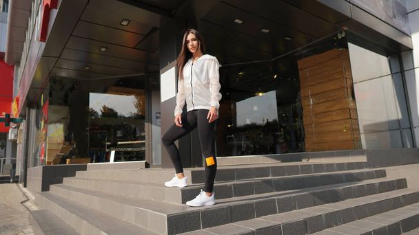 Young attractive woman in white blouse and legging pant in front of store. - Photo, Image