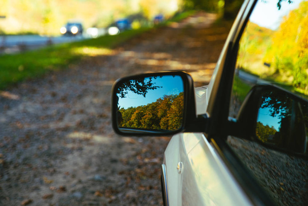αυτοκίνητο κοντά αντανάκλαση των κίτρινων δέντρων στο δρόμο καθρέφτη ταξίδι - Φωτογραφία, εικόνα