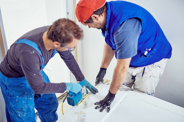 Δύο άντρες που δουλεύουν μαζί σε μια ανακαίνιση σπιτιών.. - Φωτογραφία, εικόνα