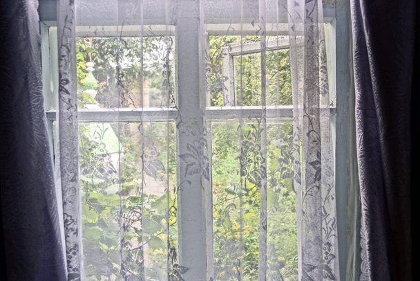 Het raam in de kamer is bedekt met een transparant gordijn - Foto, afbeelding