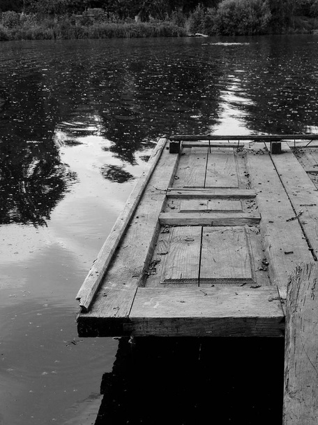 Puente gris de madera sobre el agua del embalse
 - Foto, Imagen