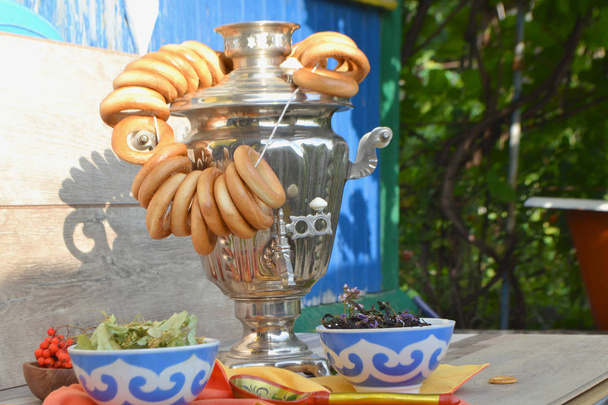 Rosyjski tradycyjny samowar z kolorowych pączki i Bajgle z herbatą ziołową na drewnianym tle shabby - Zdjęcie, obraz