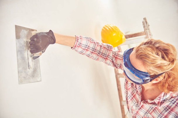 Рабочая женщина штукатурка / покраска стен внутри дома
. - Фото, изображение