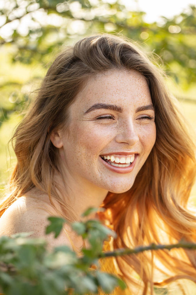 Happy girl with freckles posing in sunny garden. - Fotografie, Obrázek