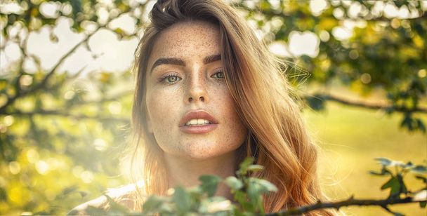 Sensual girl with freckles posing in sunny garden. - Zdjęcie, obraz