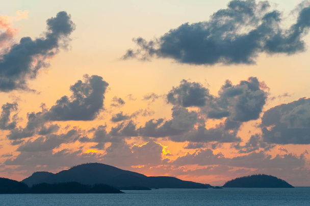 Whitsunday Islands Sunset - view from Hamilton Island across the water to Whitsunday Island. Clouds in the colourful sky at sunrise - Фото, изображение