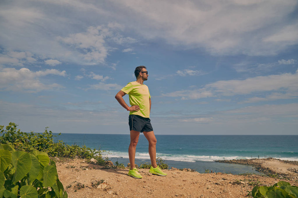 Sportsman s'étirant sur une falaise exotique tropicale près de l'océan
. - Photo, image