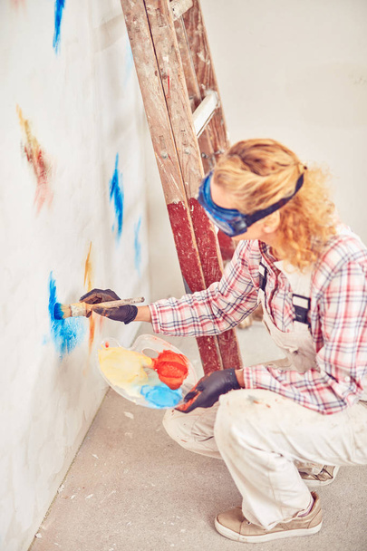 Εργασία γυναίκα πλεκτής/ζωγραφική τοίχους μέσα στο σπίτι. - Φωτογραφία, εικόνα